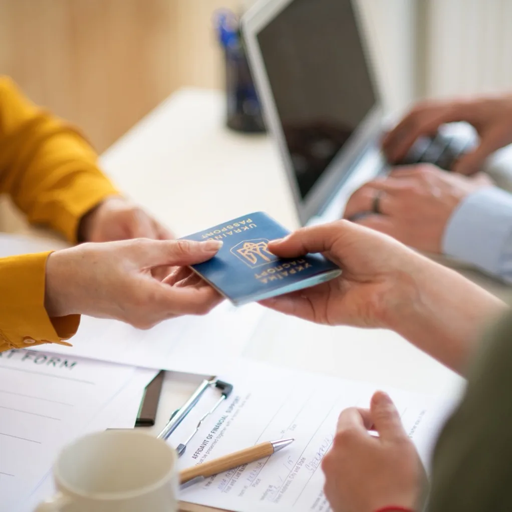 Client handing a passport across the desk during an immigration consultation