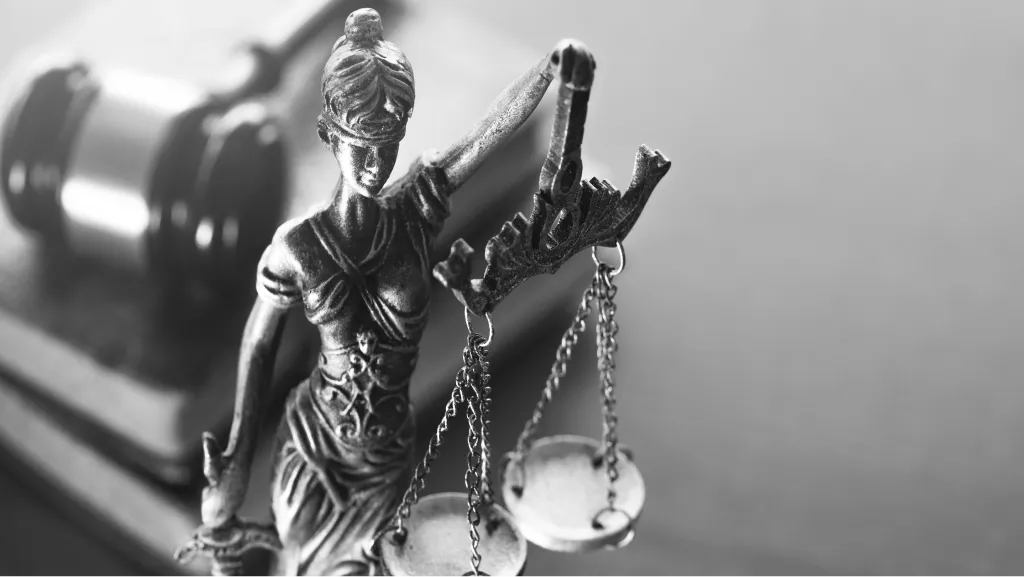 Statue of Lady Justice holding the scales beside a gavel